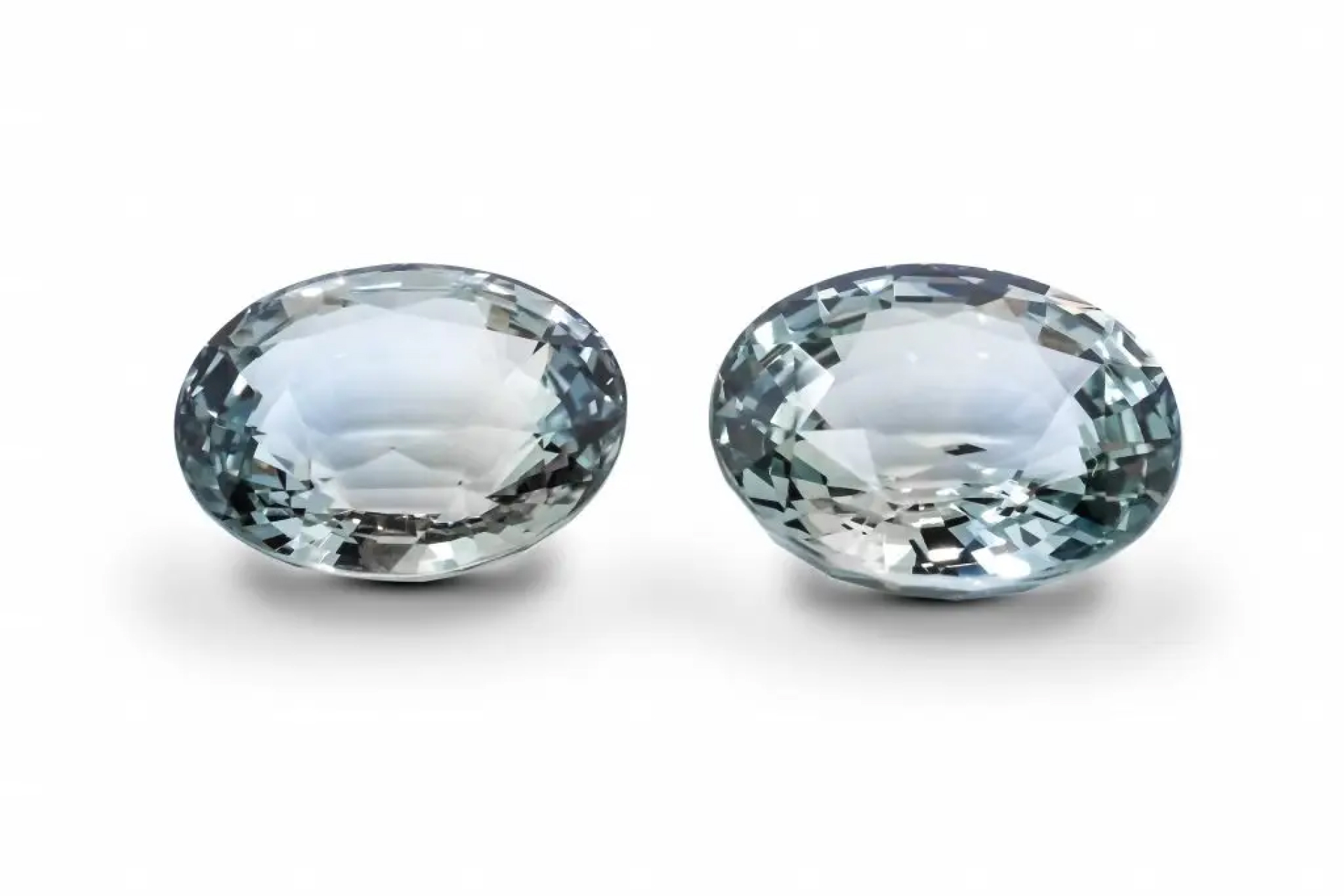 A pair of oval-cut deep blue sapphires, perfectly matched in color and cut on a white background.