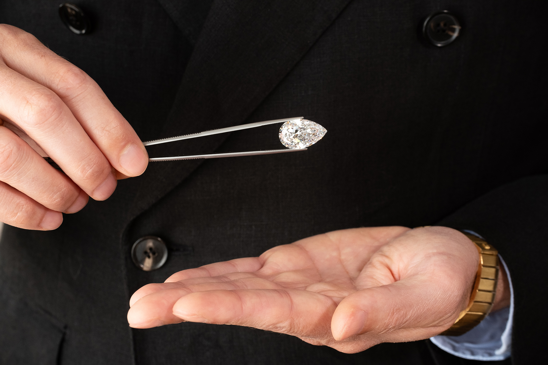 diamond in tweezers and gold watch