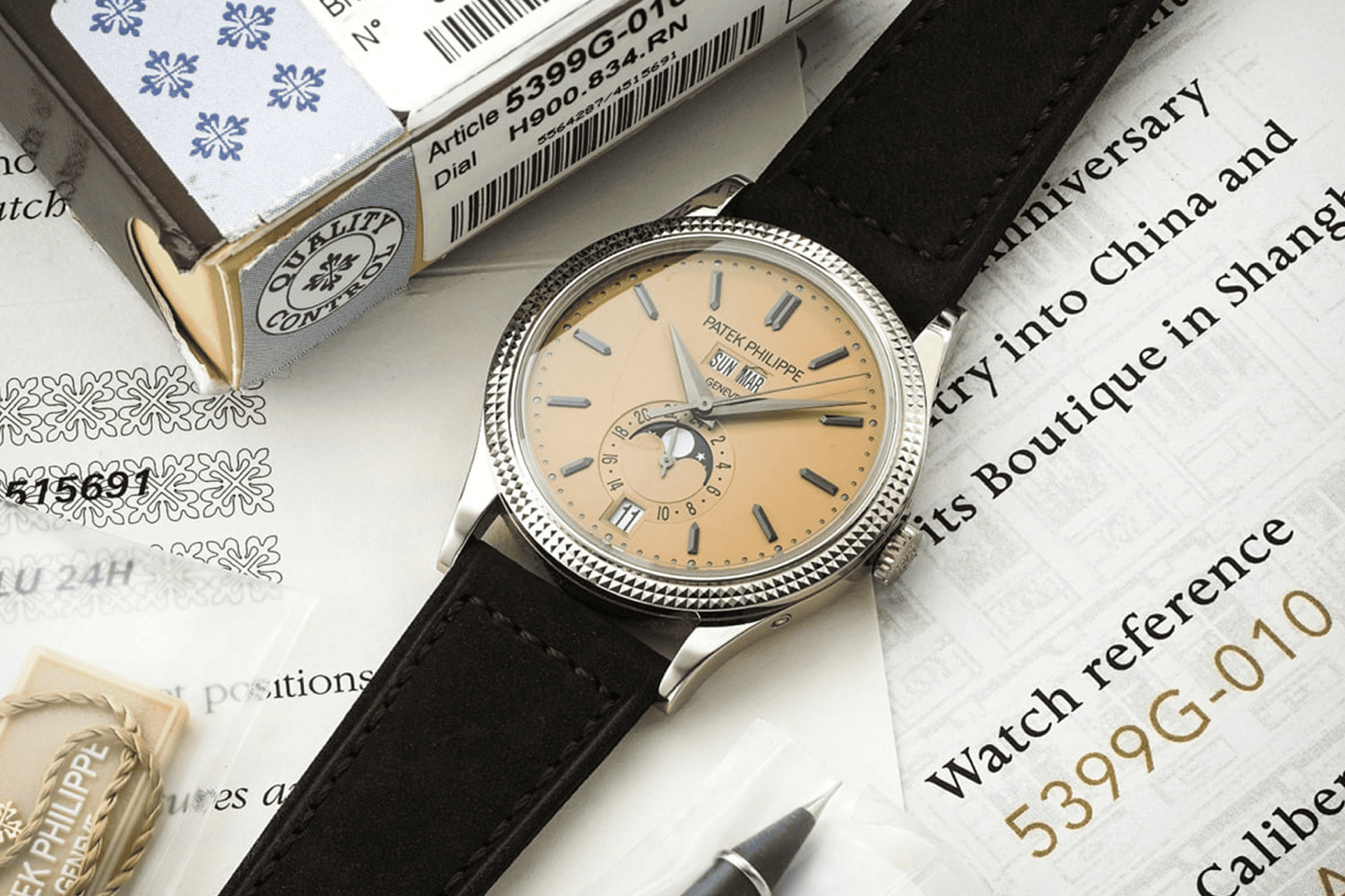 The image shows a wristwatch with a leather strap lying on a piece of paper with text and other objects.