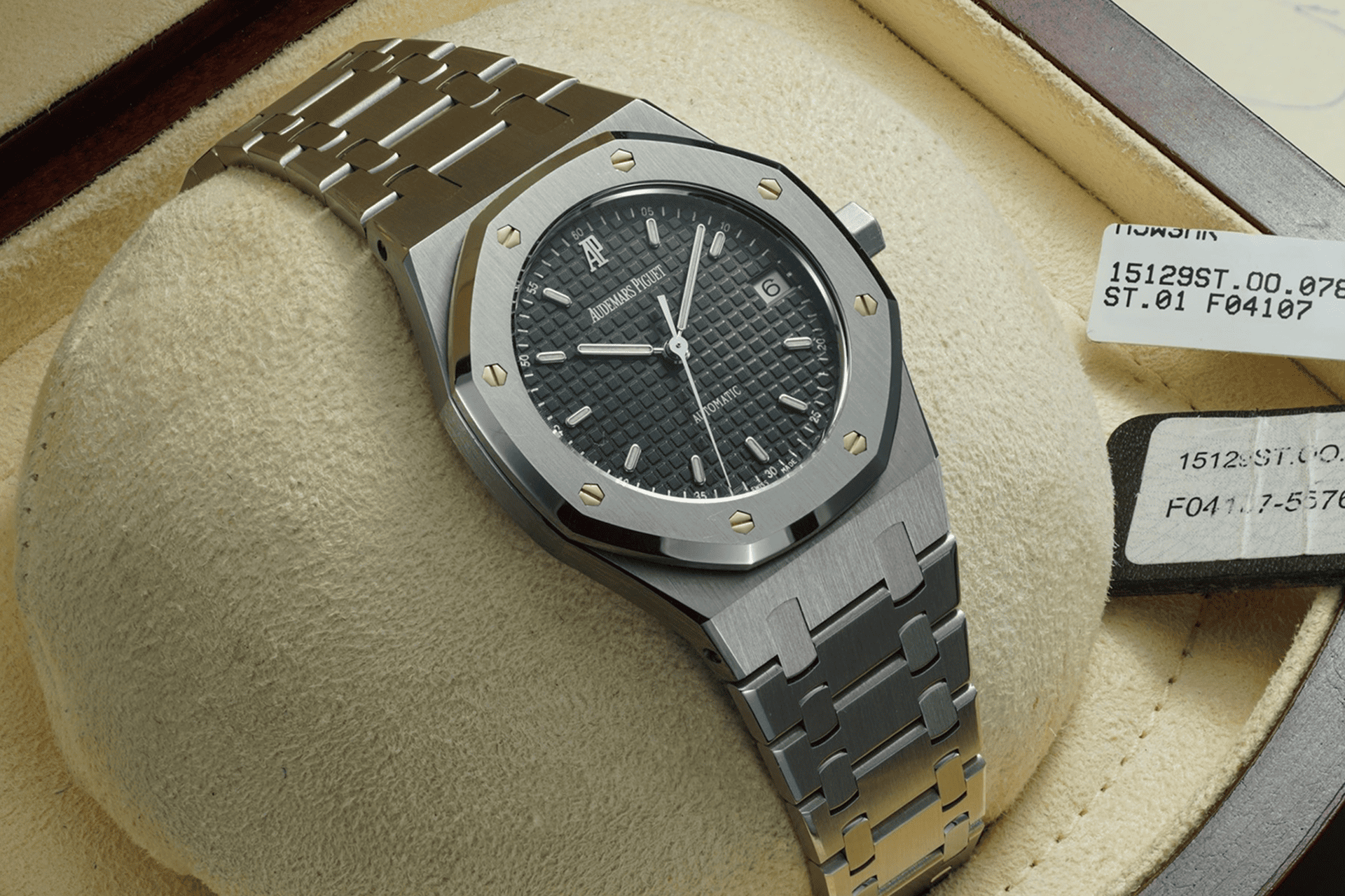 The image shows a Piquet watch in a box, with a metal bracelet and a dark dial.